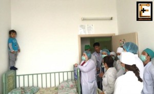 Παιδί όρθιο στο κρεβάτι φοβάται να κάνει ένεση μπροστά σε ιατρούς και νοσηλευτές. Παιδιατρικό παιδίατρος.